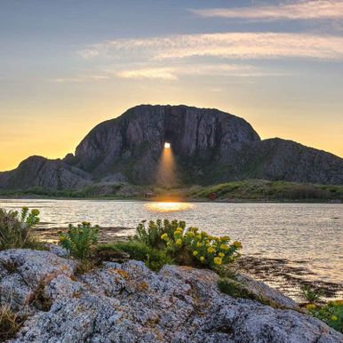 Solnedgang gjennom hull i fjellet Torghatten