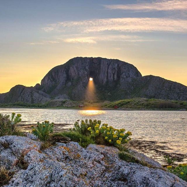 Solnedgang gjennom hull i fjellet Torghatten